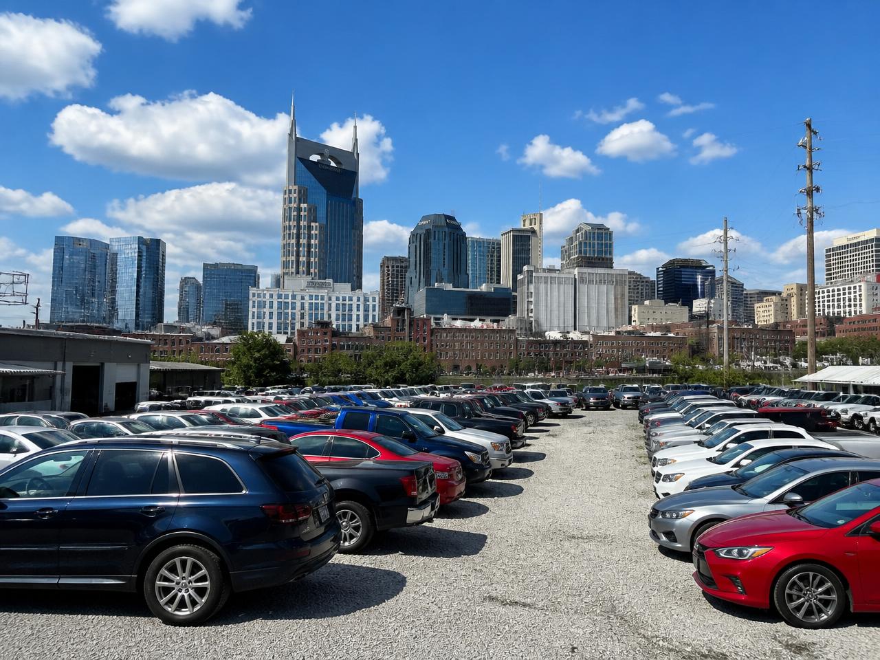 Used cars parked with the Nashville skyline on a sunny day